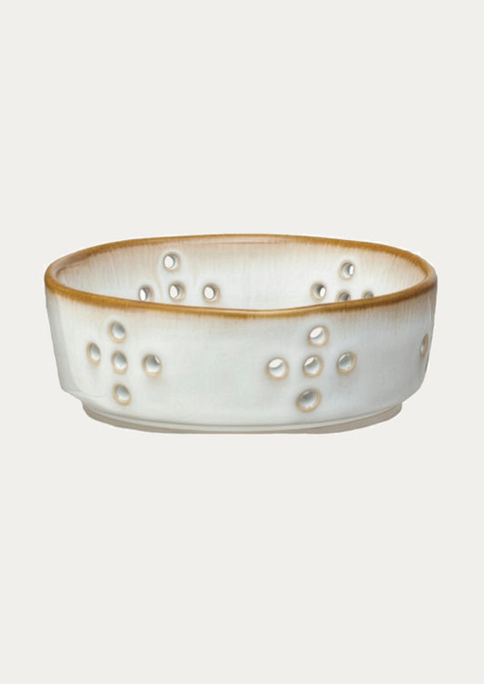 Ceramic bowl with decorative holes on a white background