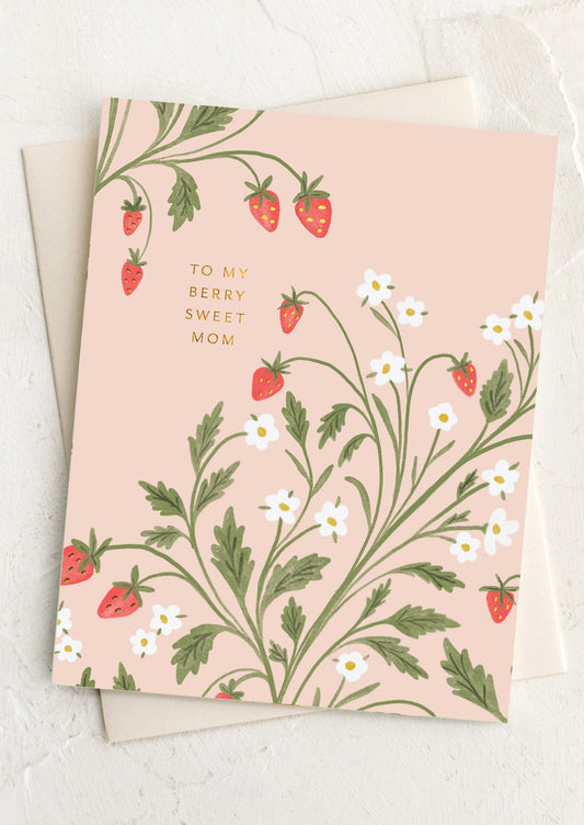 Greeting card with strawberry and daisy design and text 'To my berry sweet mom' on a light pink background.