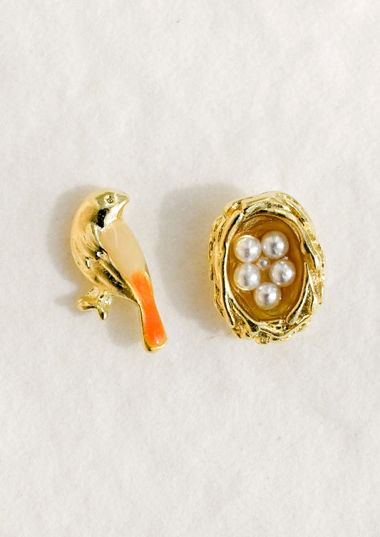 A pair of mismatched gold stud earrings in form of bird and nest.