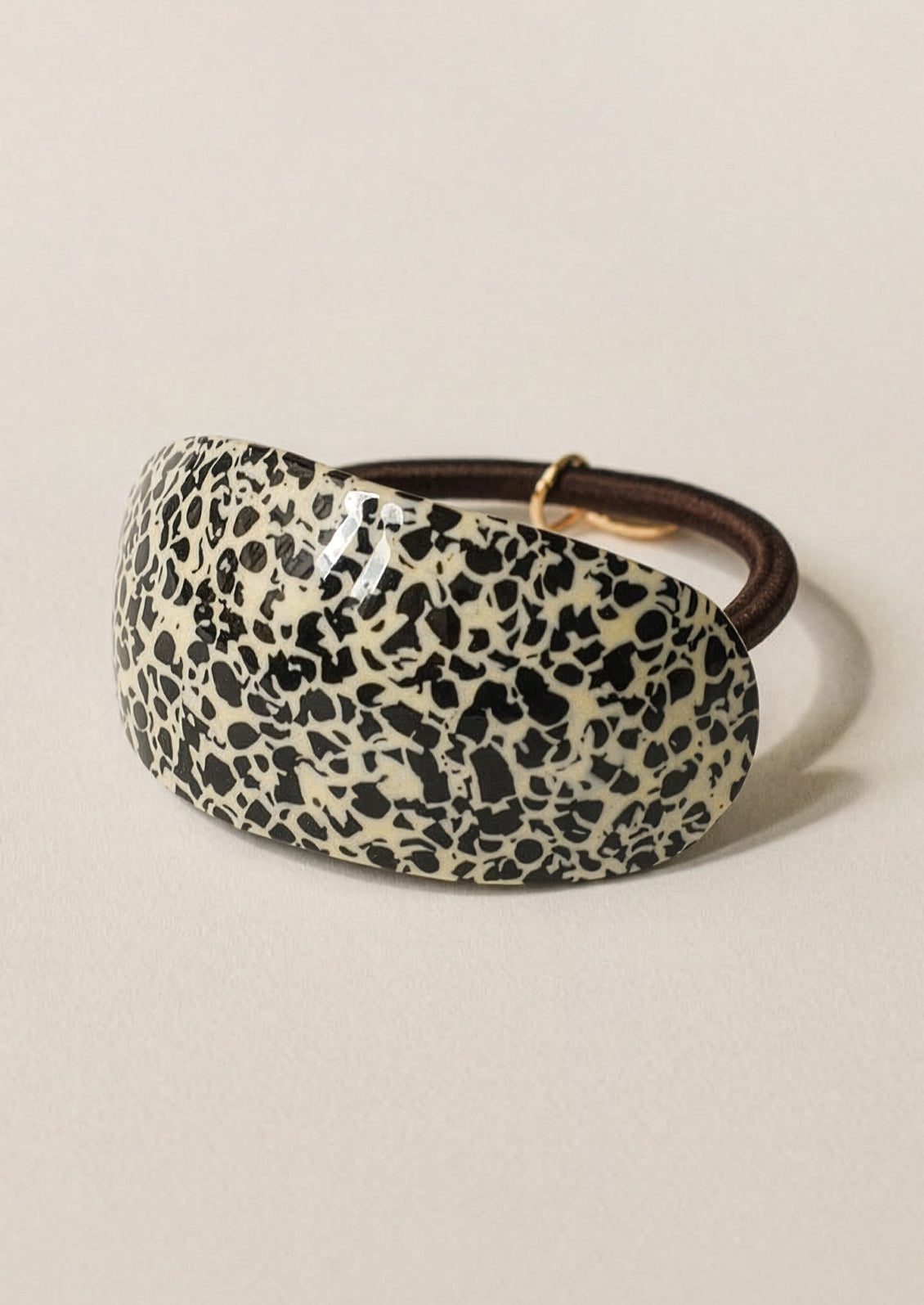 Leopard print headband with brown band on a beige background