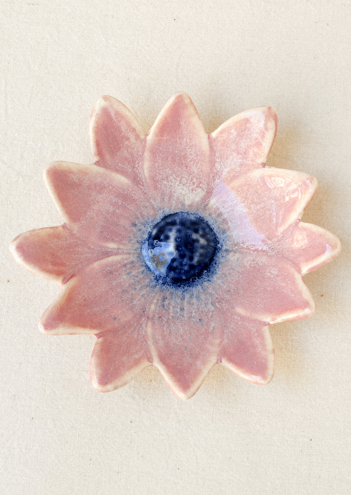 A small ceramic catchall dish in the shape of a flower in pink with a navy center.