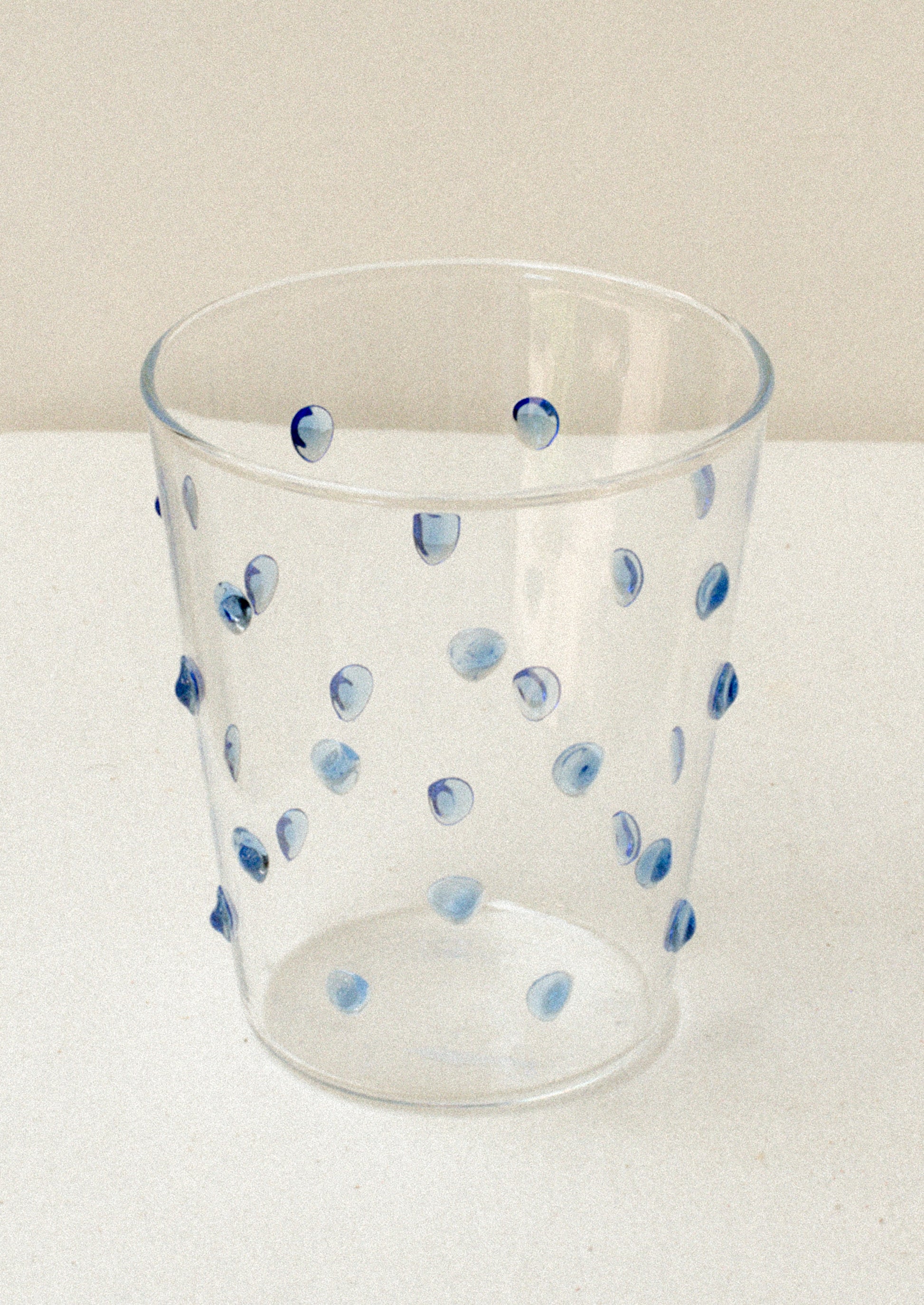 A clear glass tumblerswith textured raised dots on outside, in blue.