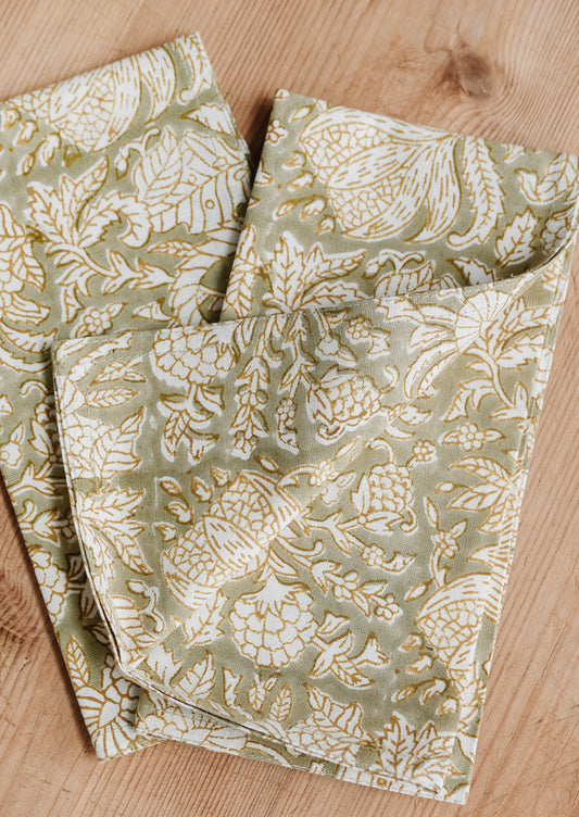 A pair of block print napkins in sage green with floral print.