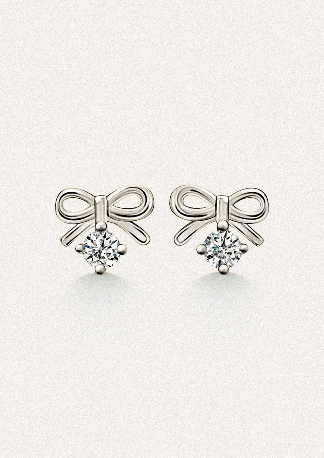 A pair of small silver stud earrings in the shape of a bow, with dangling cubic zirconia.
