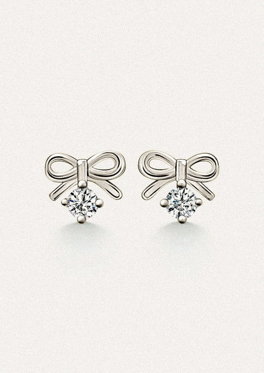 A pair of small silver stud earrings in the shape of a bow, with dangling cubic zirconia.