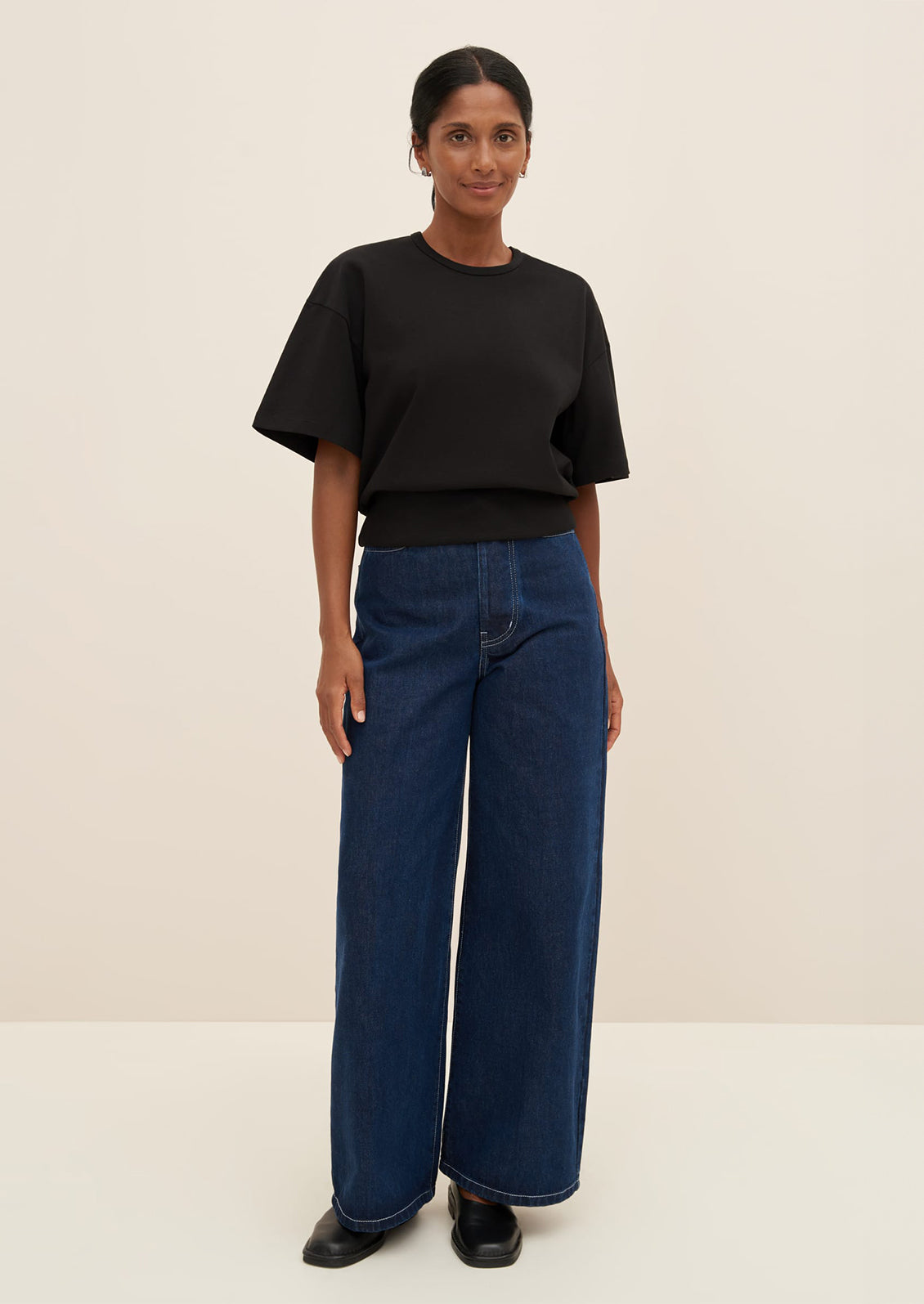 A woman wearing a boxy tee with fitted ribbed waistband, in black.