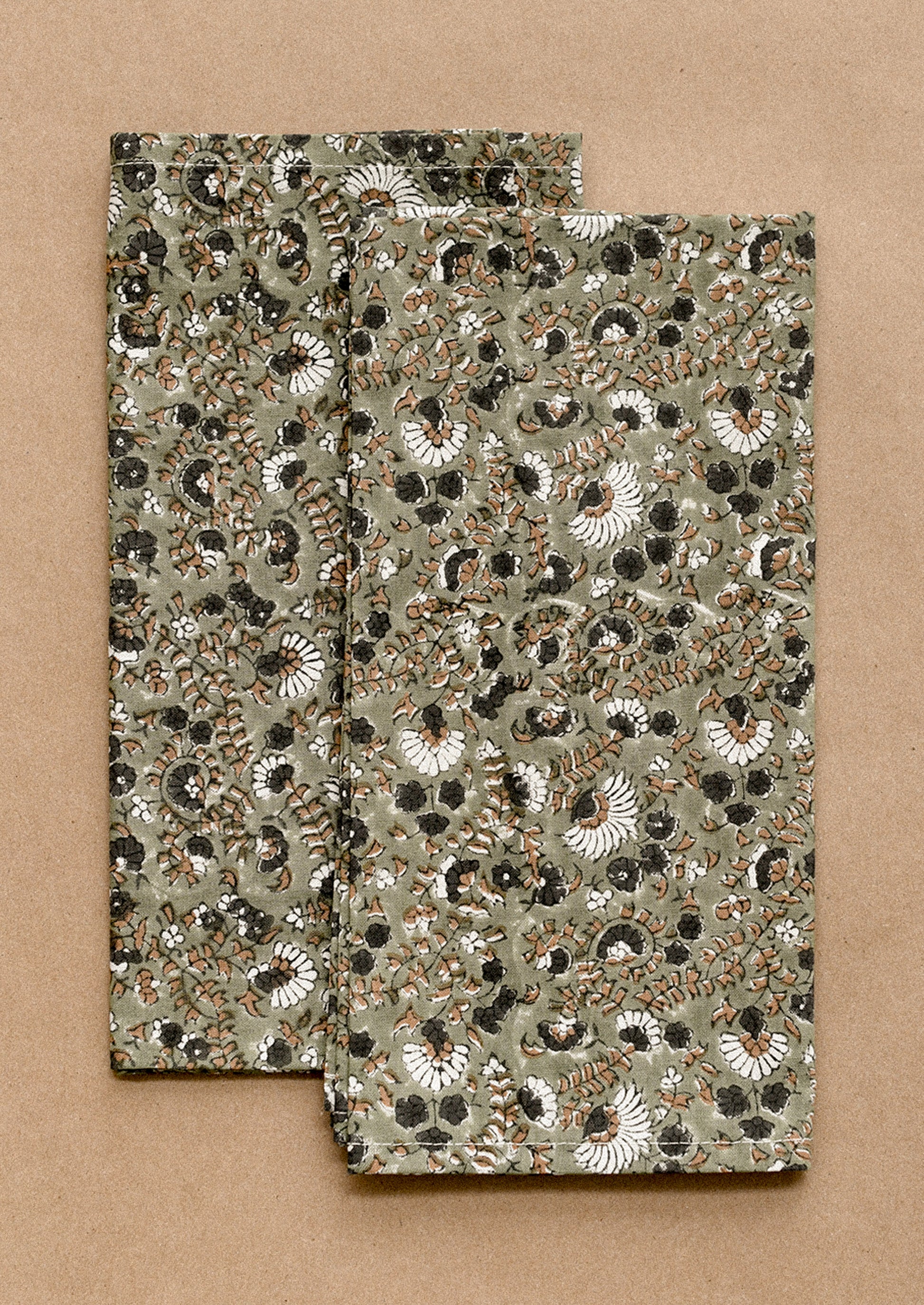Two floral patterned napkins on a brown background