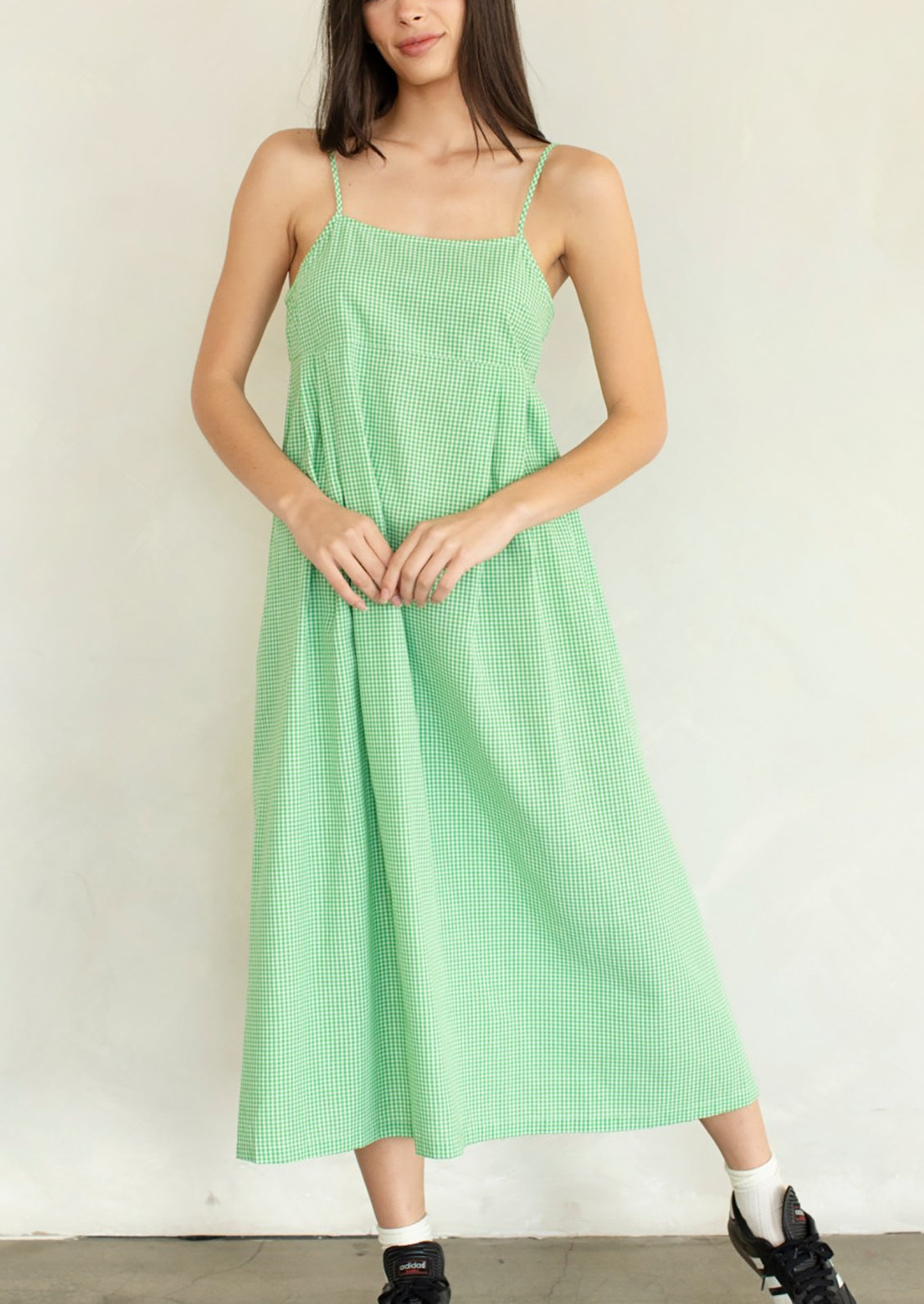 A person wearing a calf-length dress in micro green gingham.