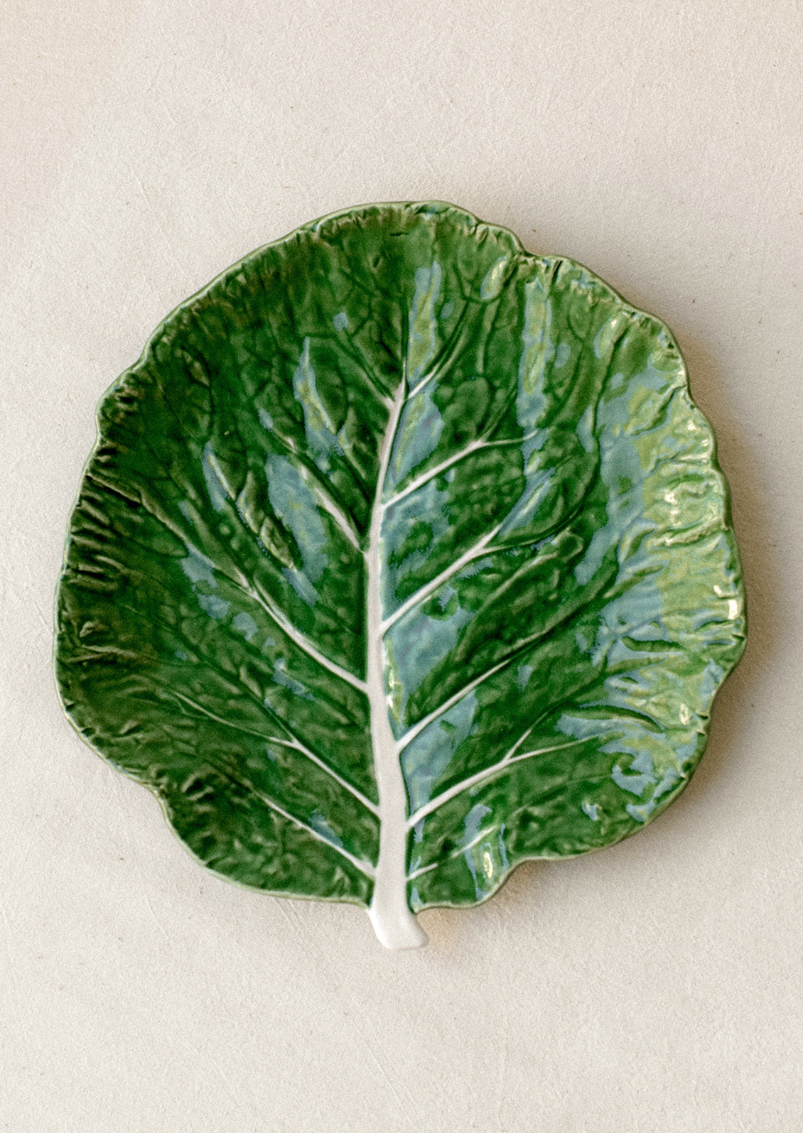 A ceramic serving "cabbageware" style salad plate that looks like green leaf of cabbage.