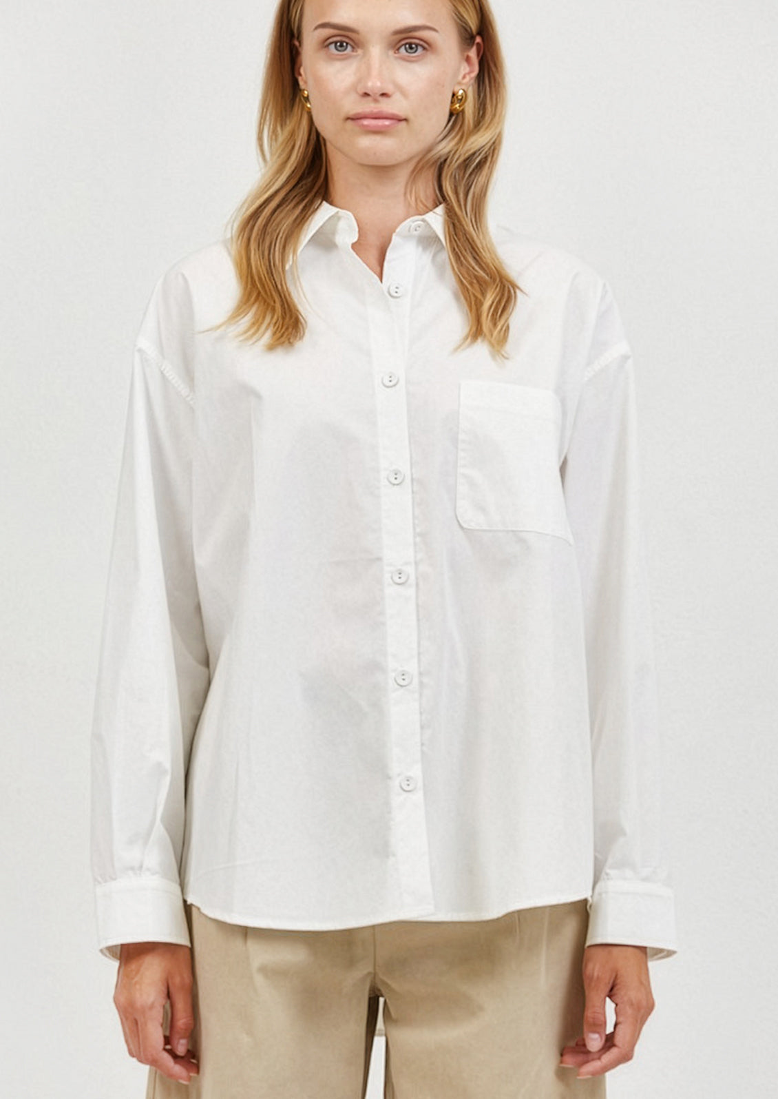 Woman wearing a white button-up shirt on a plain background