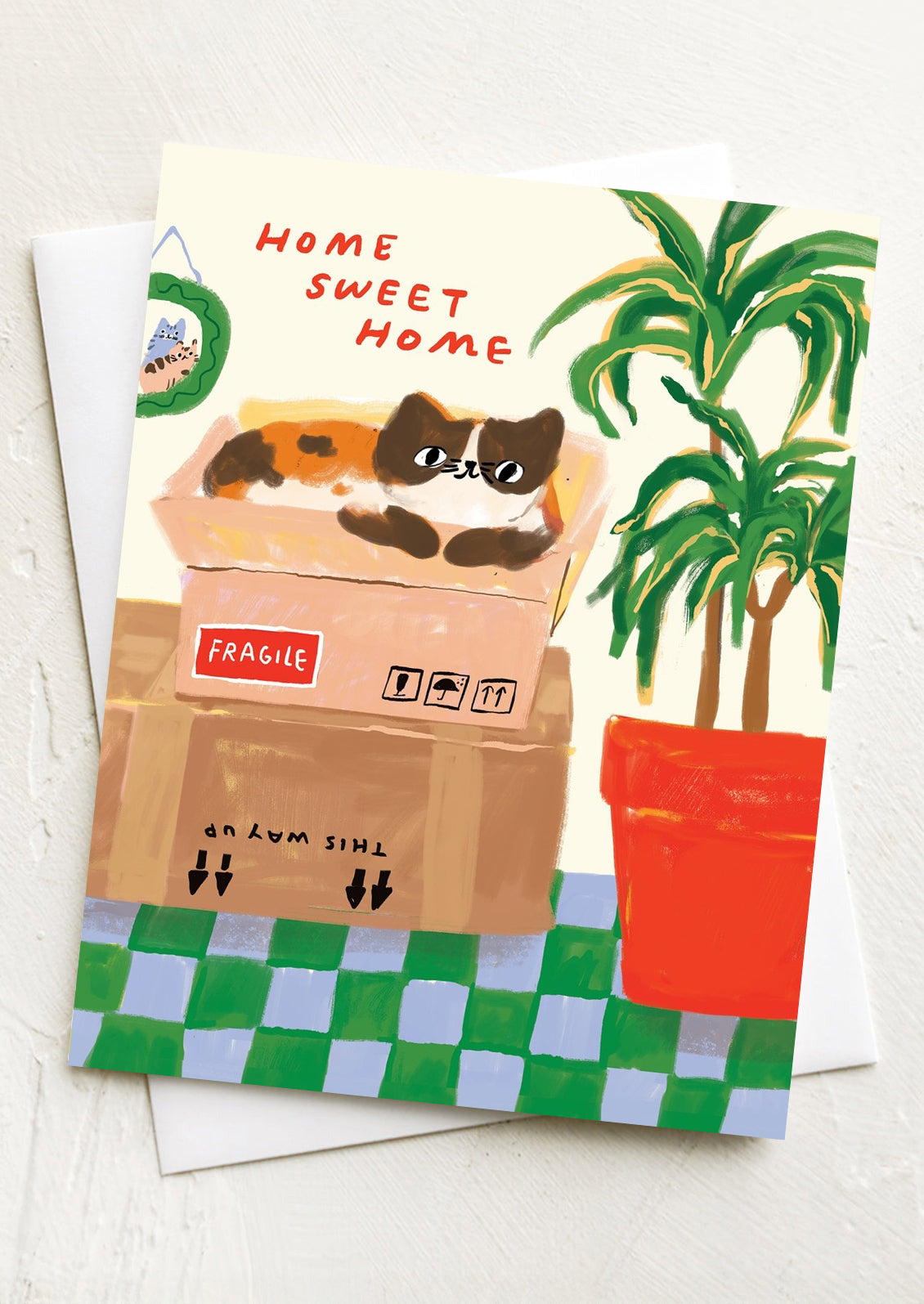 A greeting crd with illustration of cat laying on moving boxes, text reads "Home sweet home".