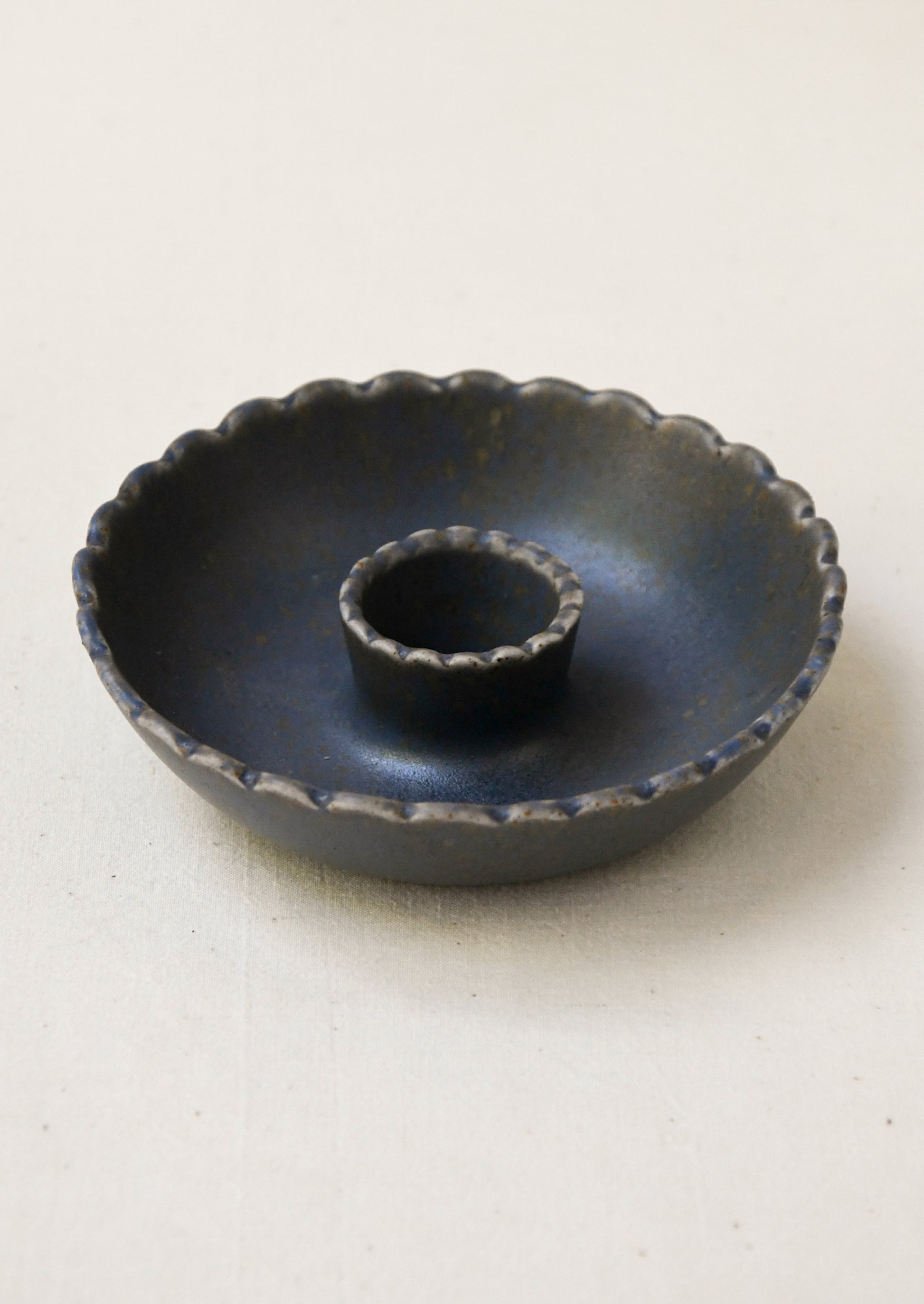 A porcelain candle holder with scalloped shape in black.