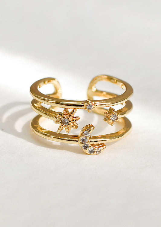 A gold triple band ring with star and moon detailing.