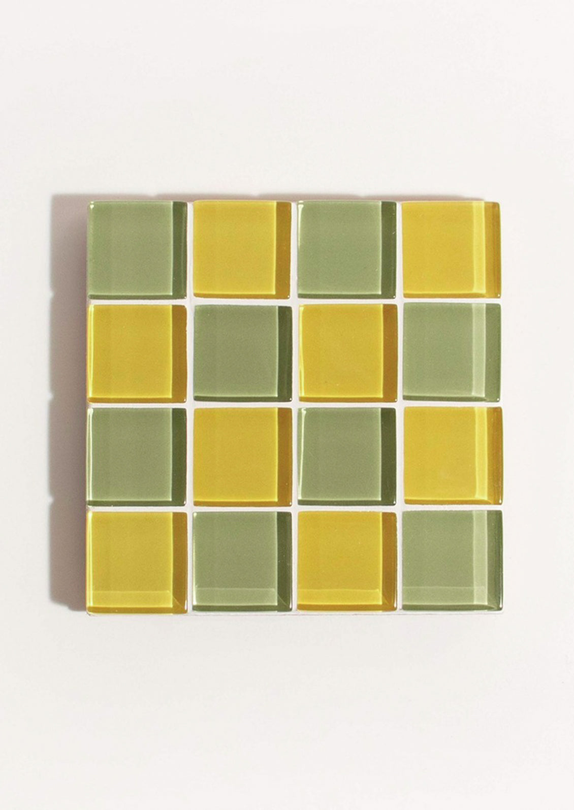 A glass tile coaster in two tone checker pattern in yellow and olive green.