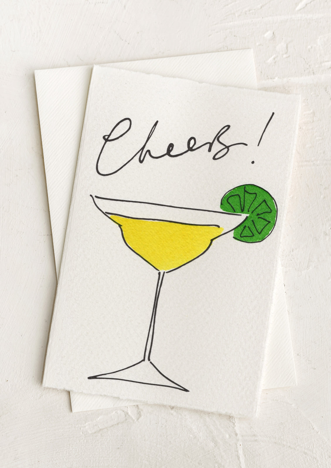 A greeting card with hand painted illustration of a martini, text above reads "Cheers!".