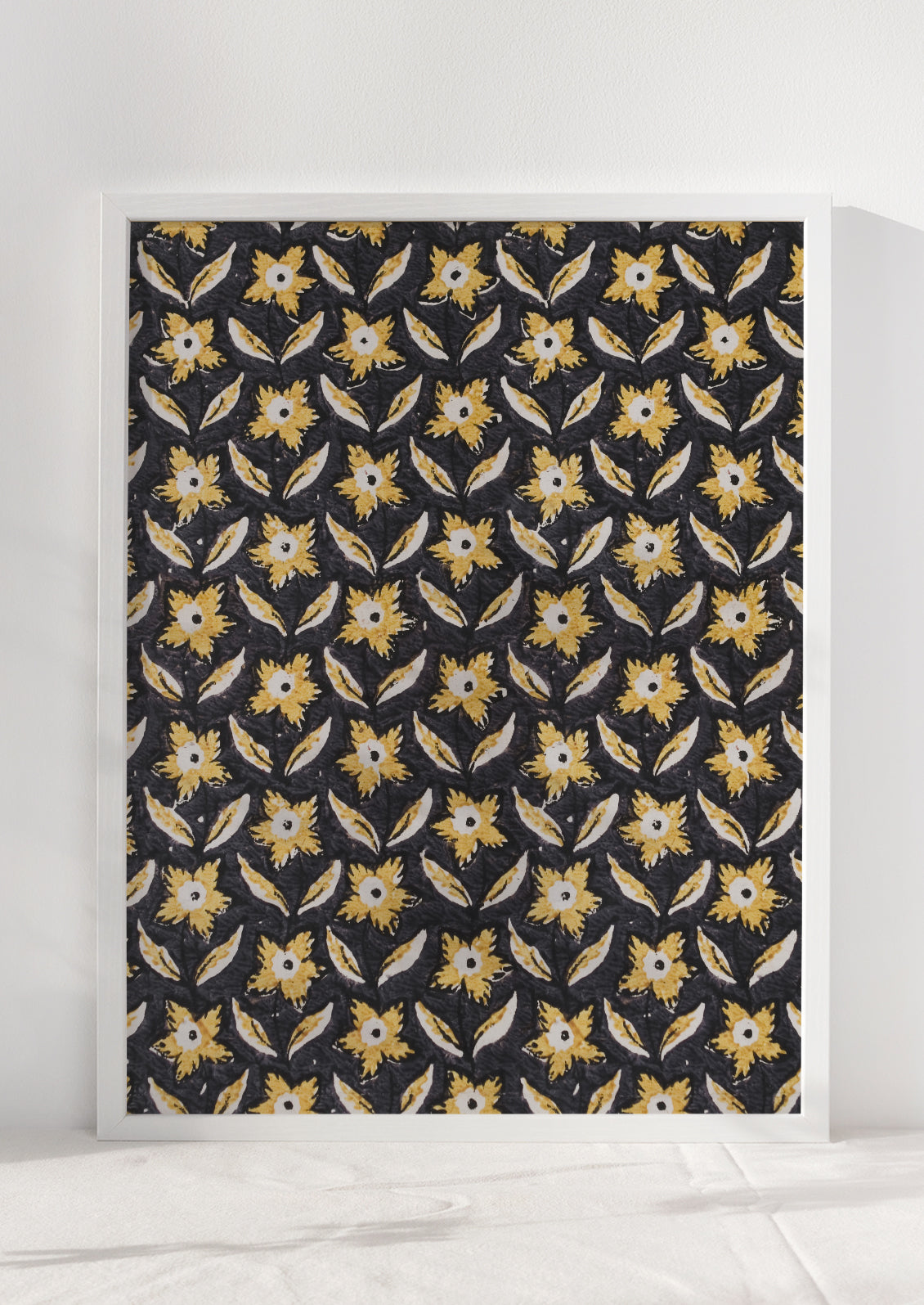 A block print textile inspired art print with black background and marigold colored flowers, framed.