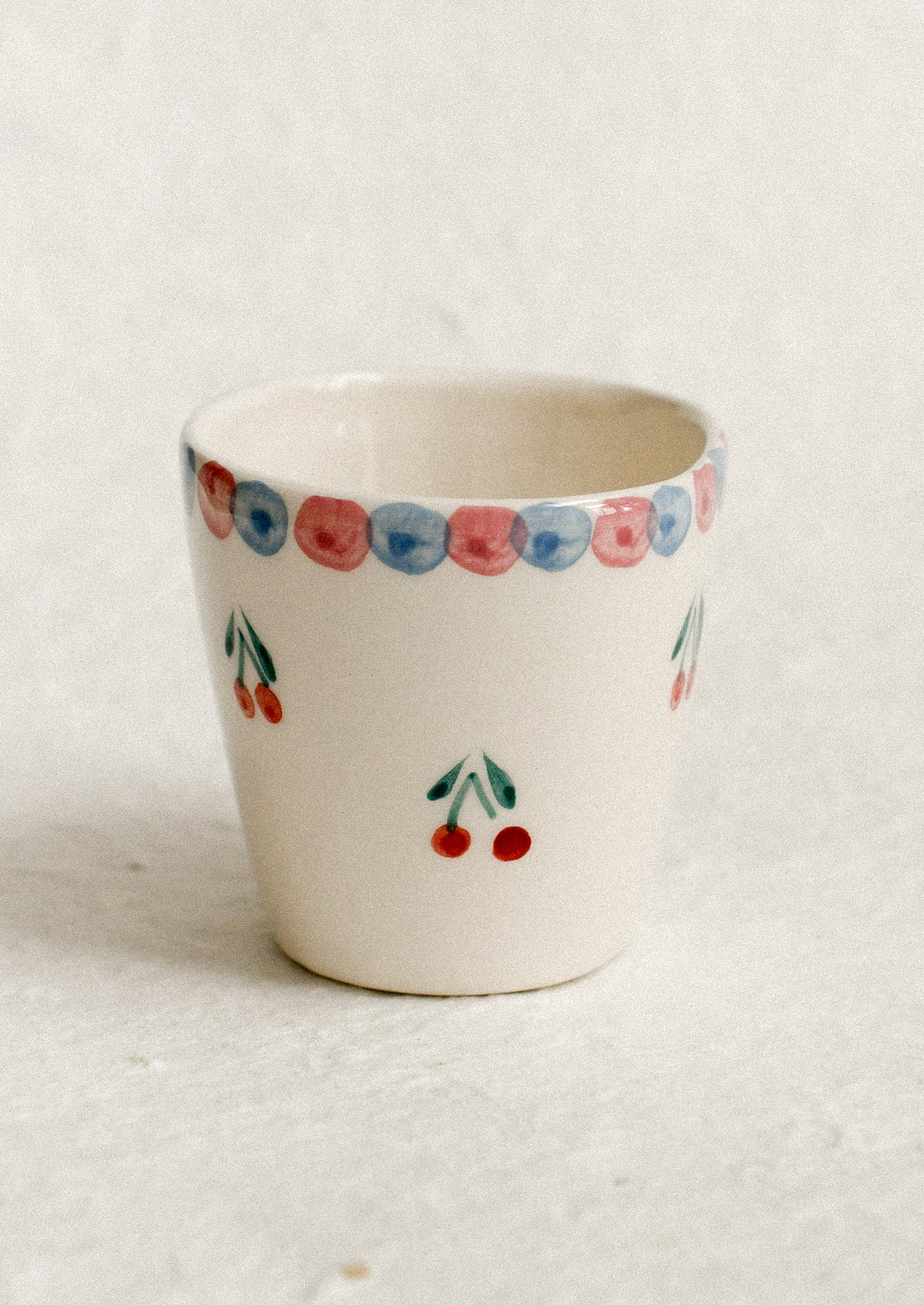 A small hand painted cup with cherry motif.
