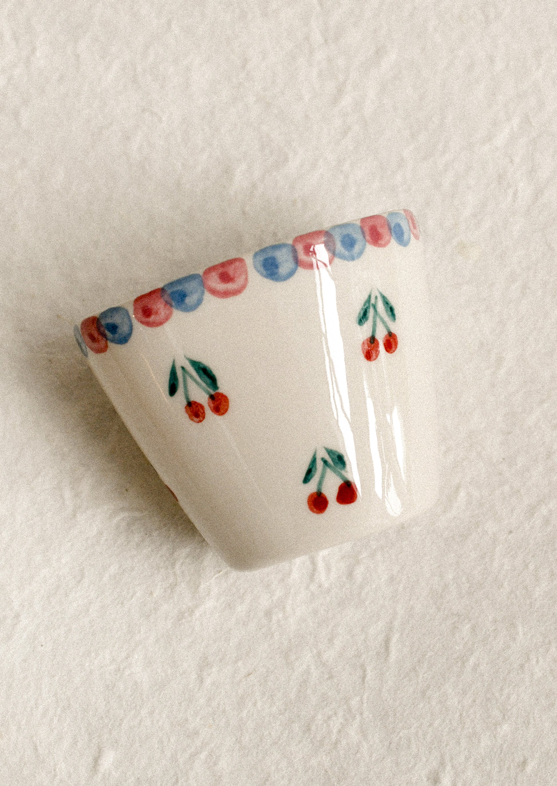 A small hand painted cup with cherry motif.