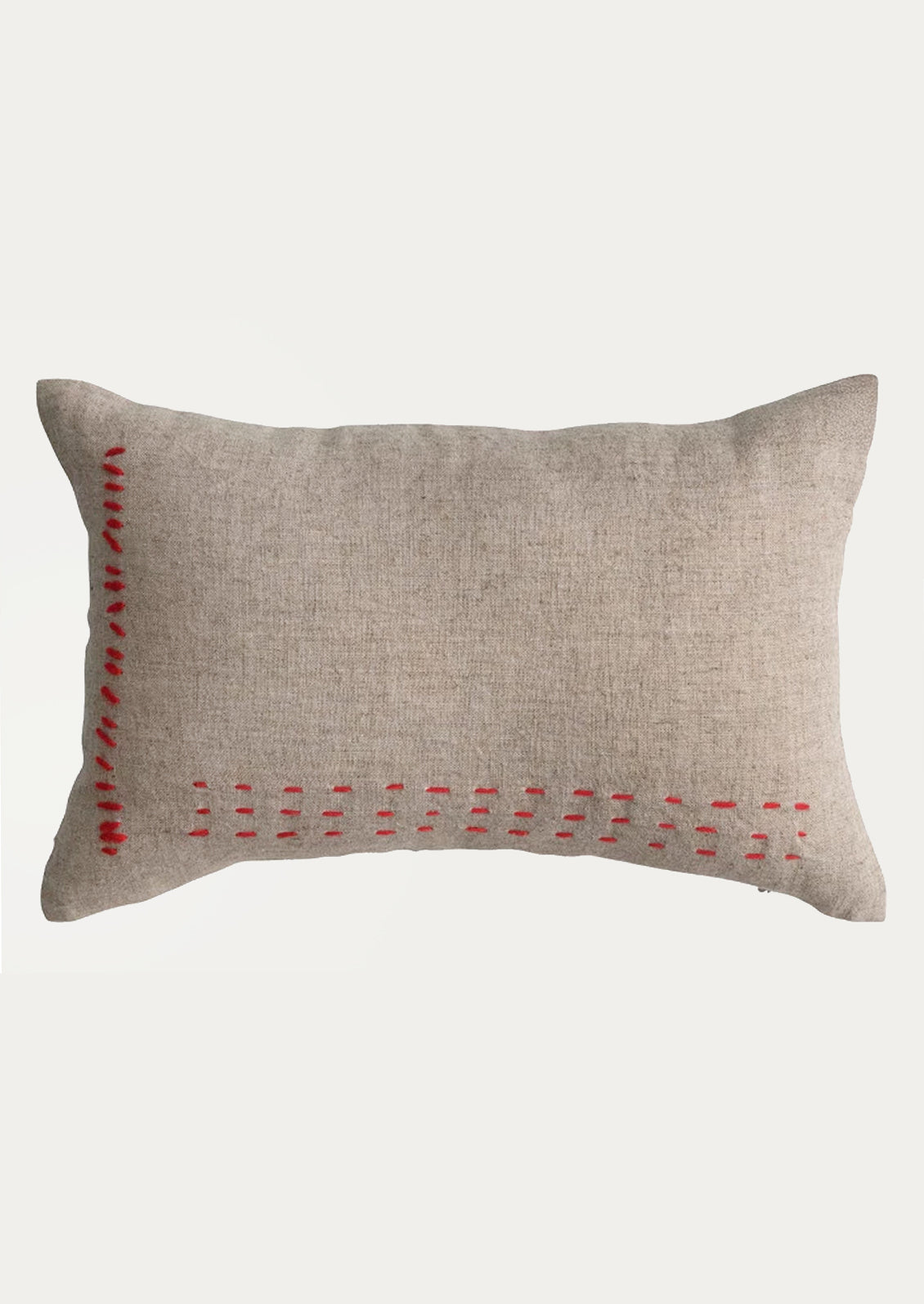 A linen lumbar pillow in natural linen with red stitching.