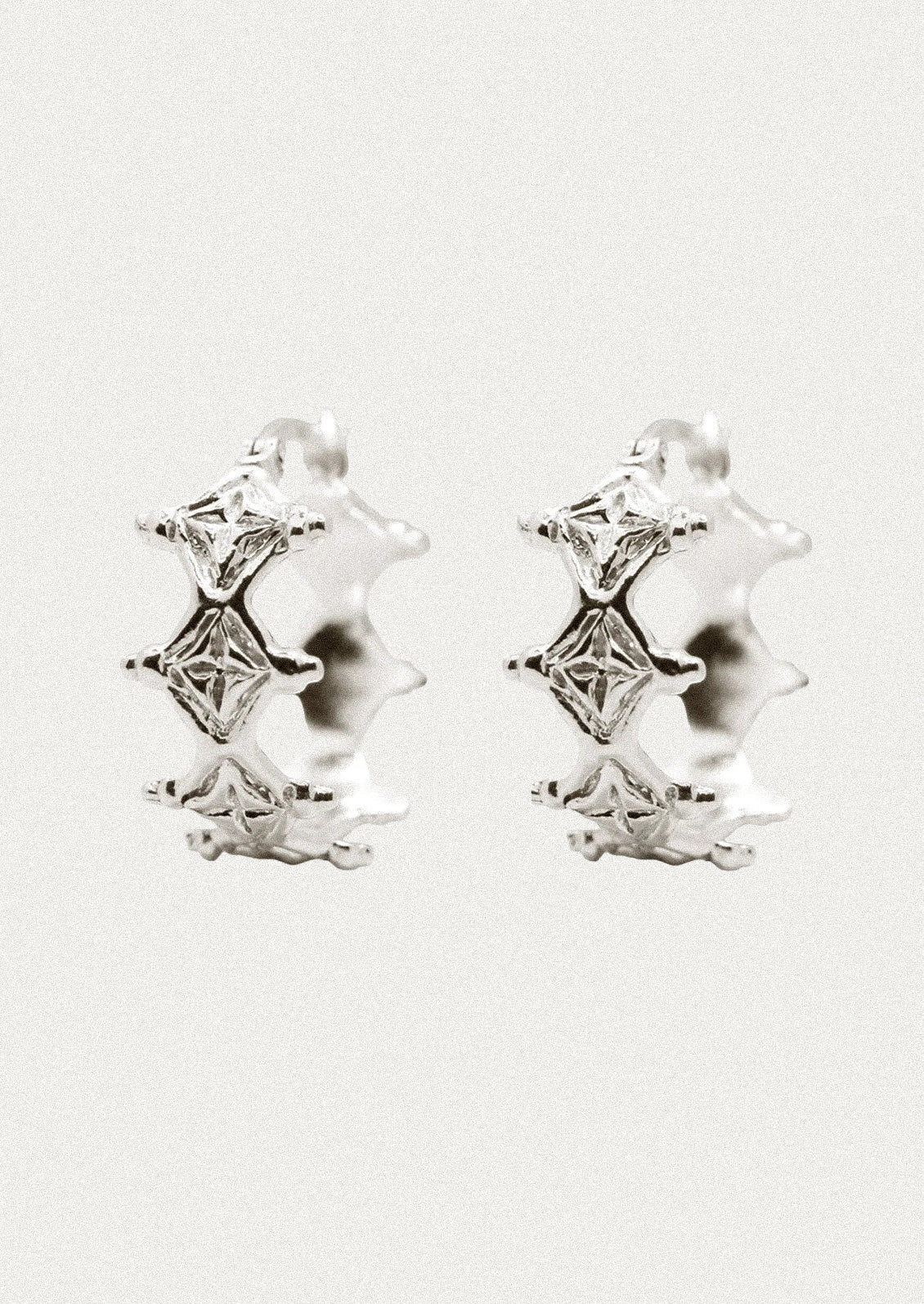 A pair of sterling silver hoop earrings with a unique diamond-like design.