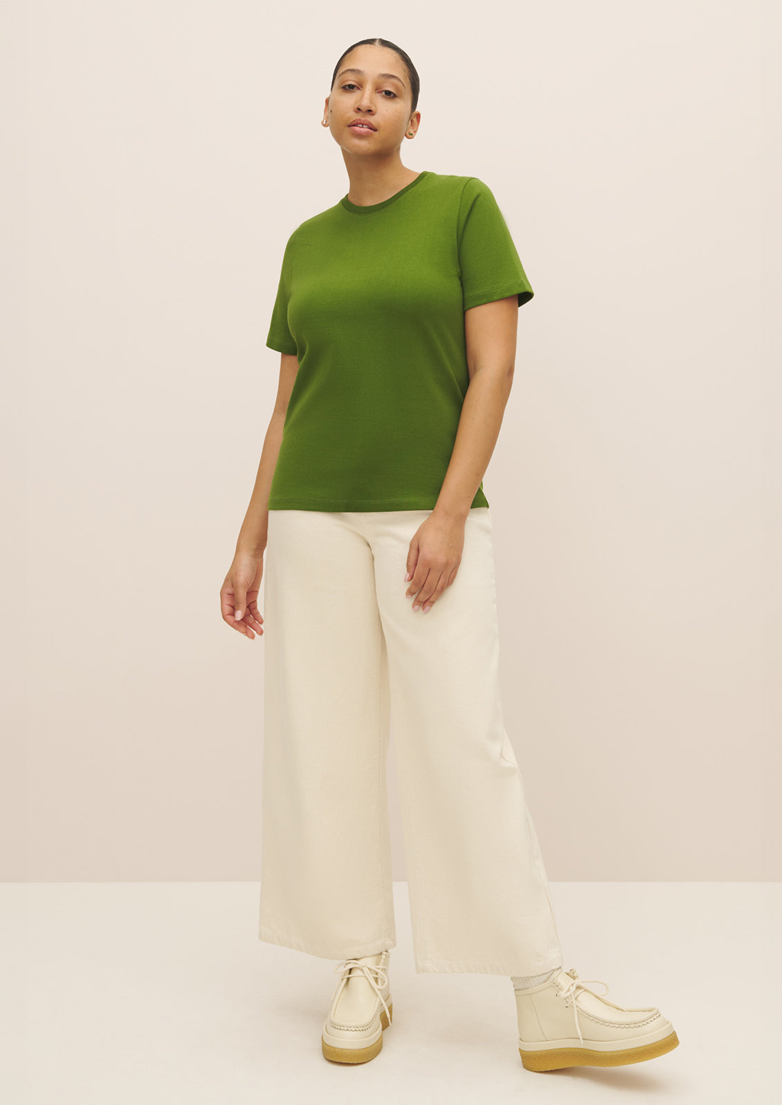 A woman wearing a knit cotton jersey short sleeve tee in vibrant green color.