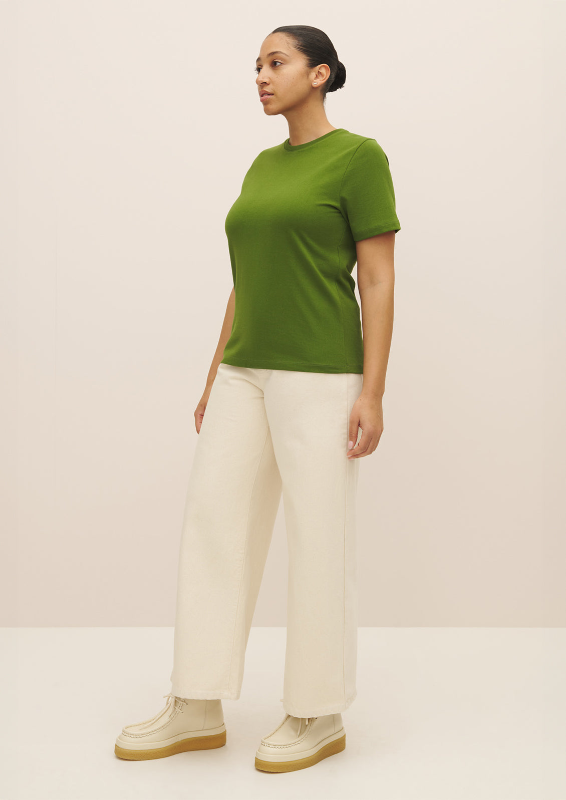 A woman wearing a knit cotton jersey short sleeve tee in vibrant green color.