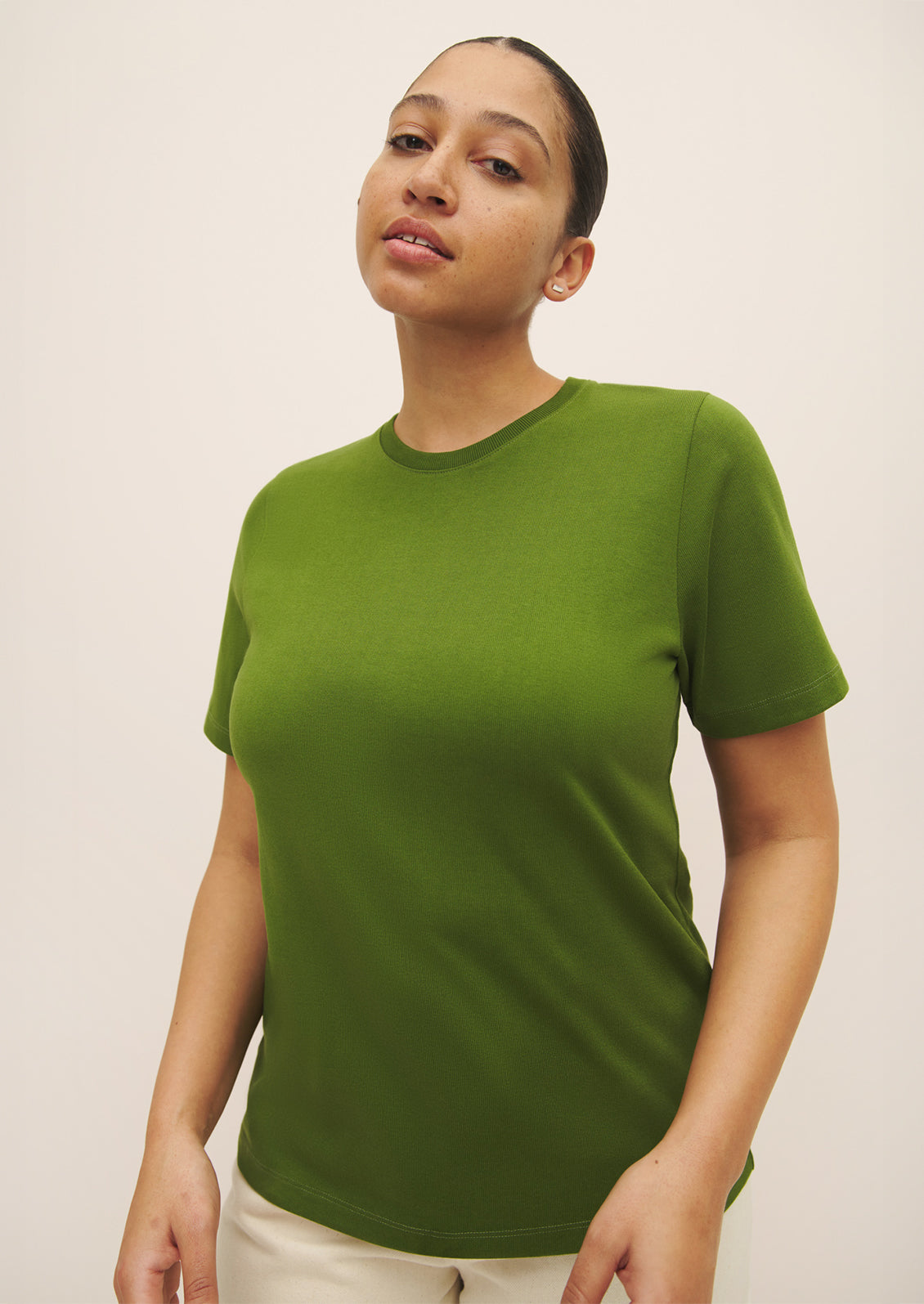 A woman wearing a knit cotton jersey short sleeve tee in vibrant green color.