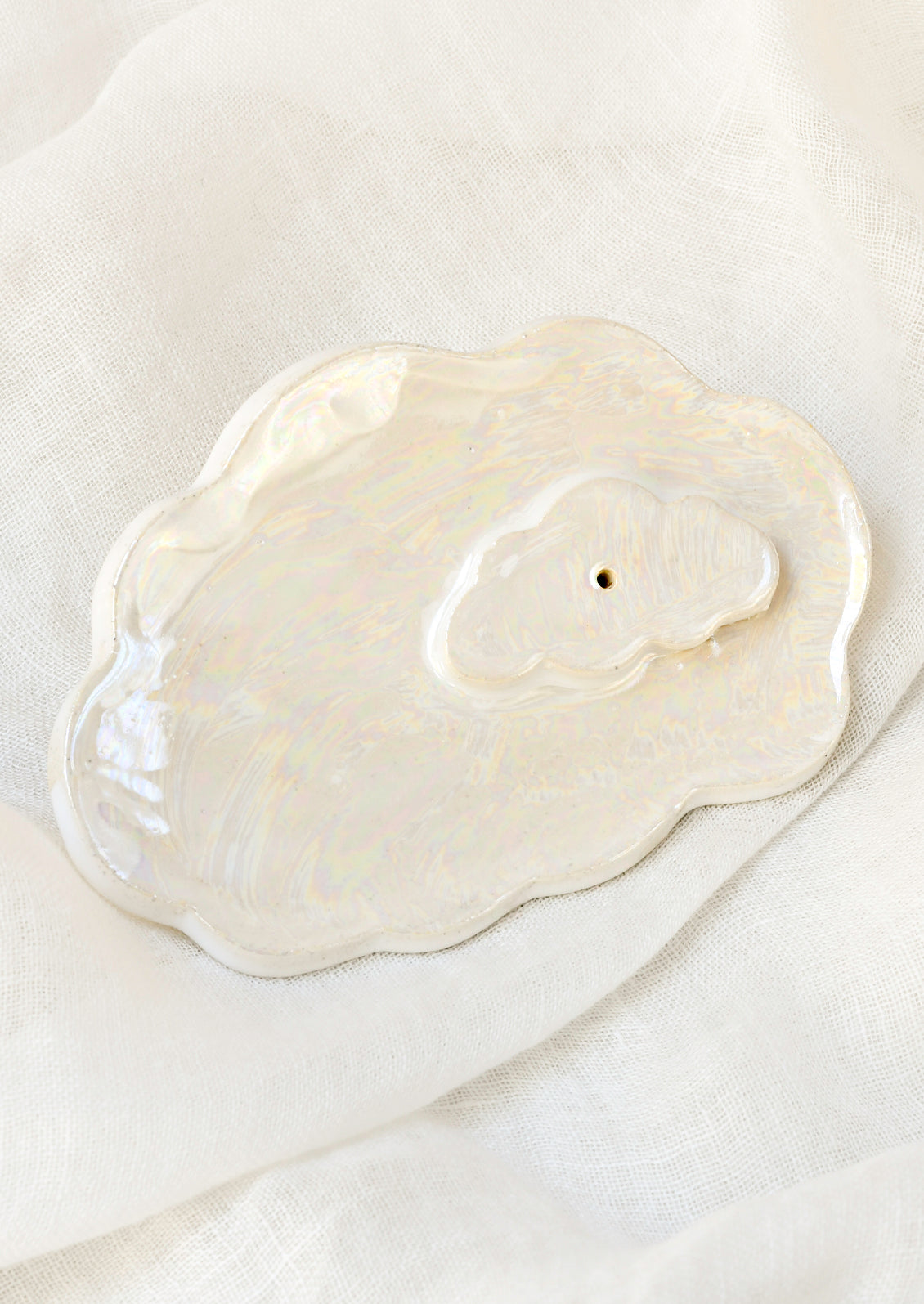 A white ceramic iridescent cloud-shaped incense holder.
