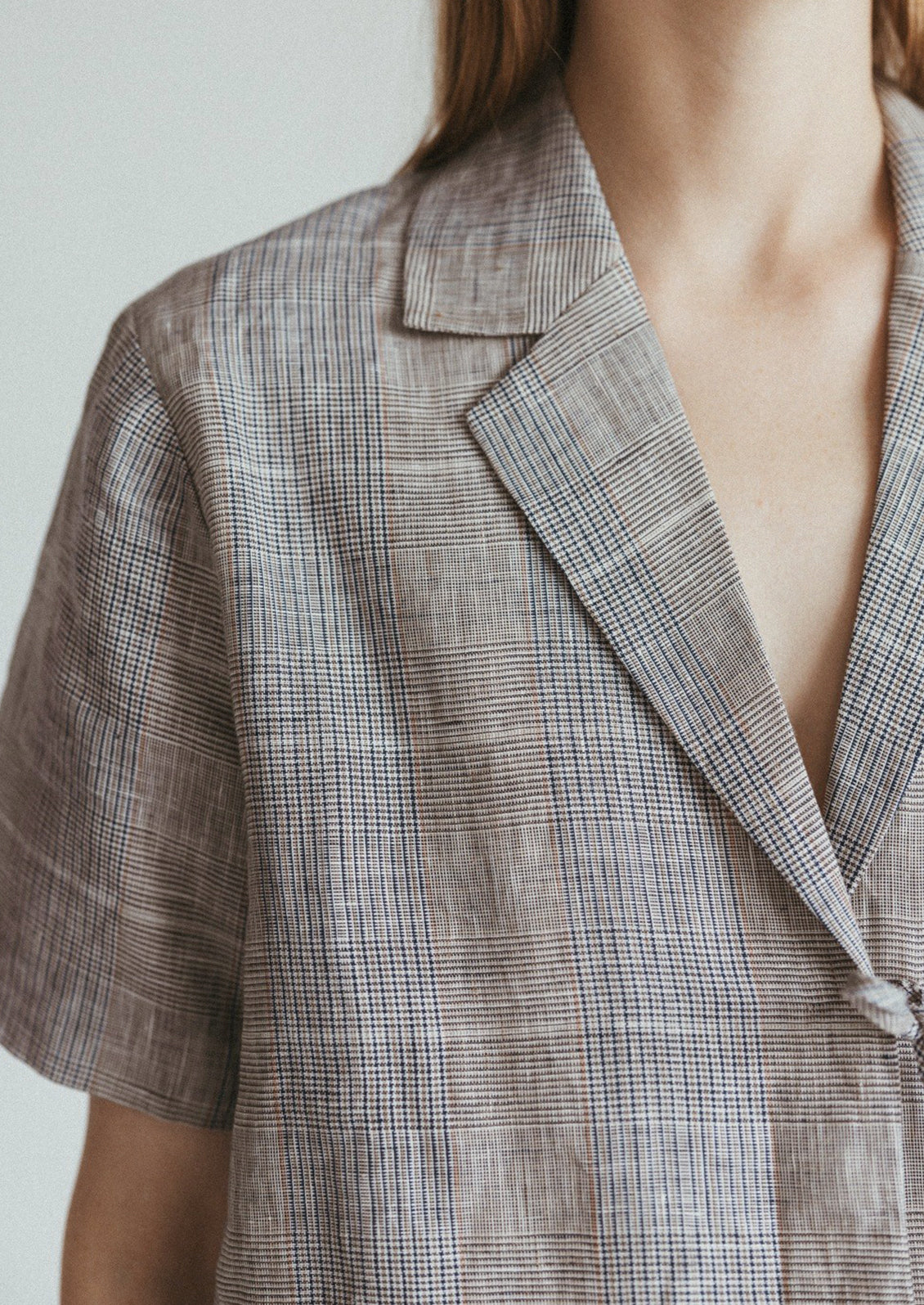 A woman wearing a linen plaid shirt with notched label and tie front.