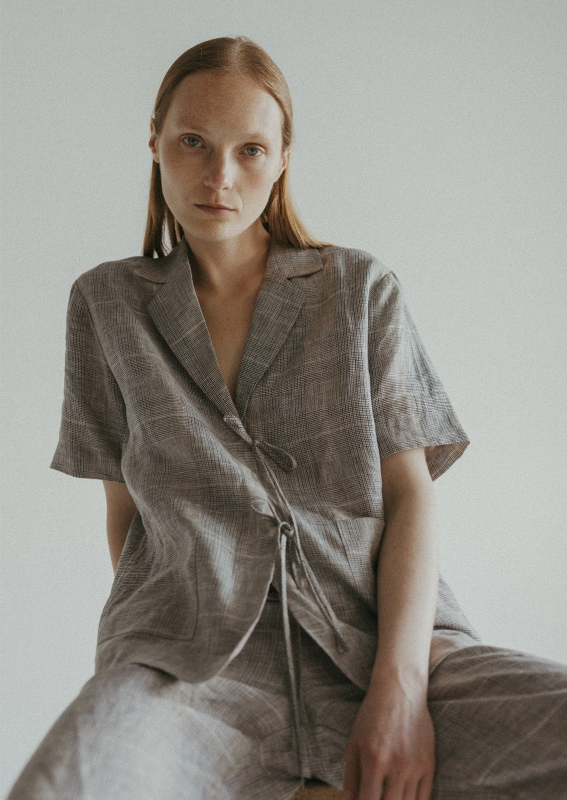 A woman wearing a linen plaid shirt with notched label and tie front.