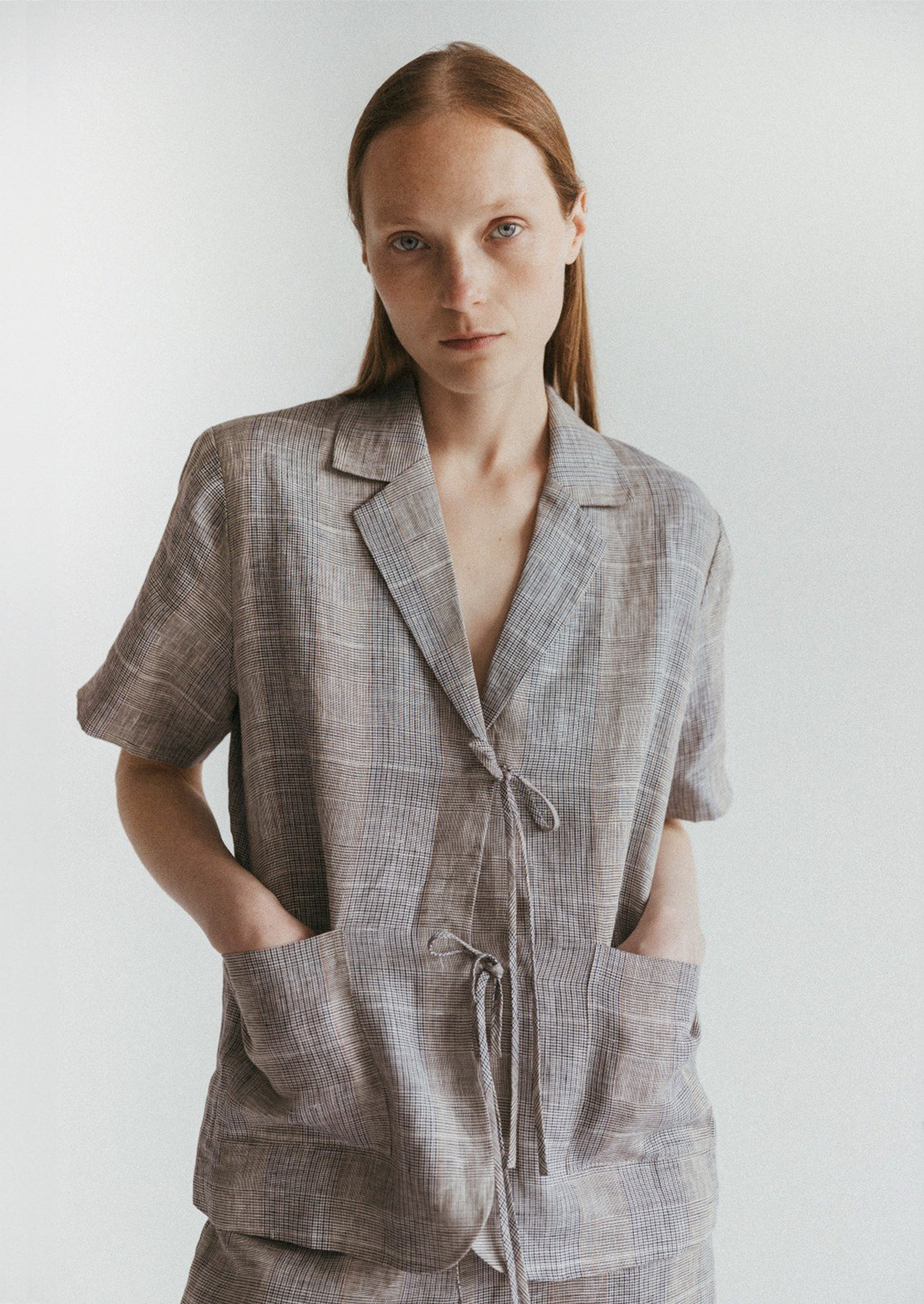 A woman wearing a linen plaid shirt with notched label and tie front.