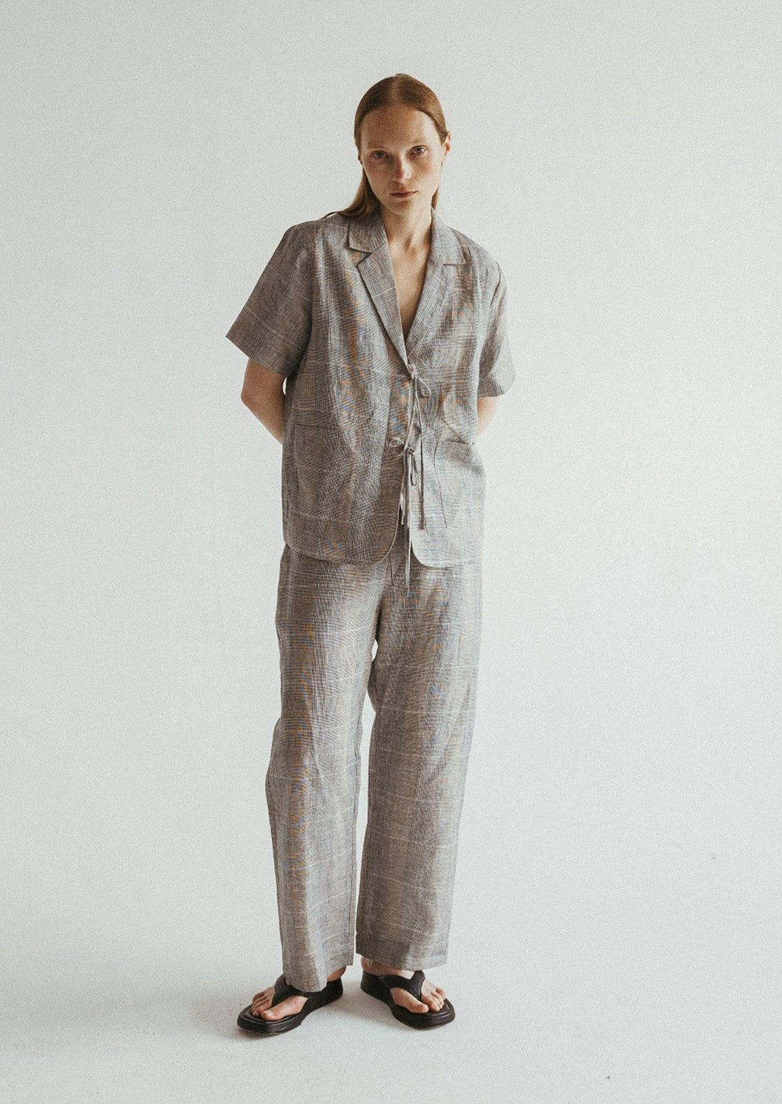 A woman wearing a linen plaid shirt with notched label and tie front.