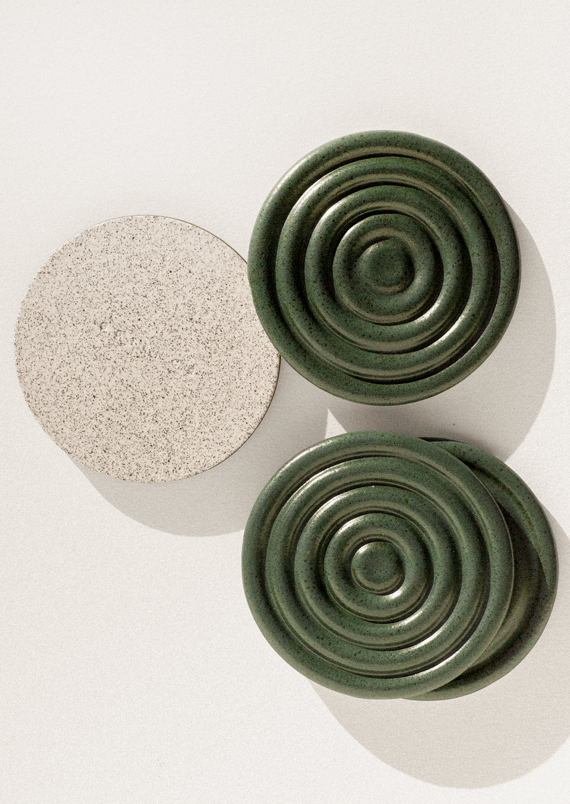 Handmade speckled ceramic coasters with a concentric design in forest green.
