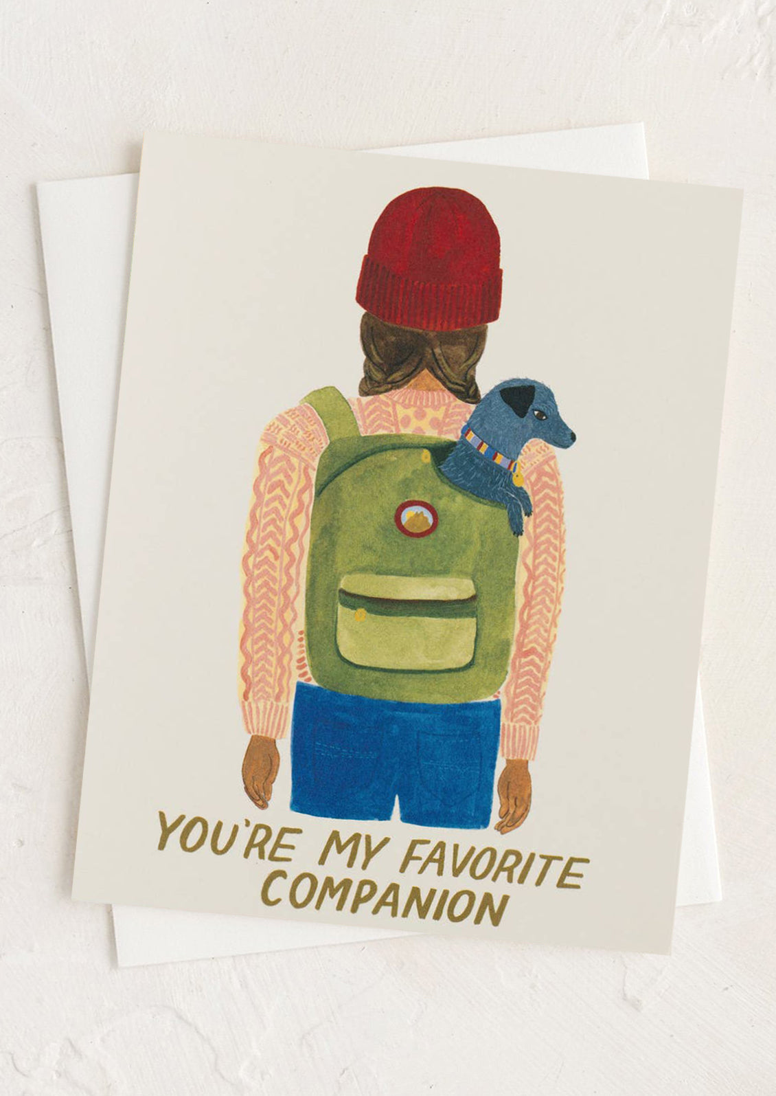 Card with illustration of person wearing a green backpack and red beanie, holding a blue dog, with text 'You're my favorite companion' on a white background.