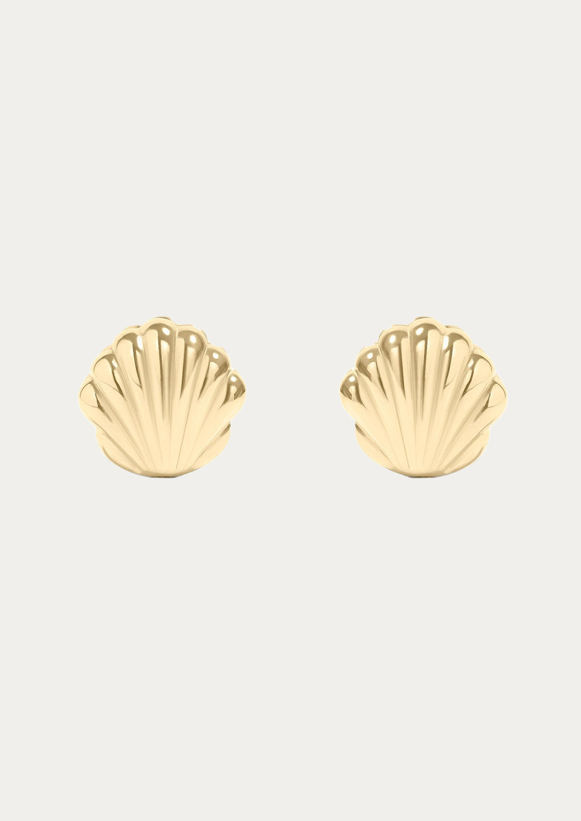A pair of gold huggie earrings in the shape of a concha shell 
