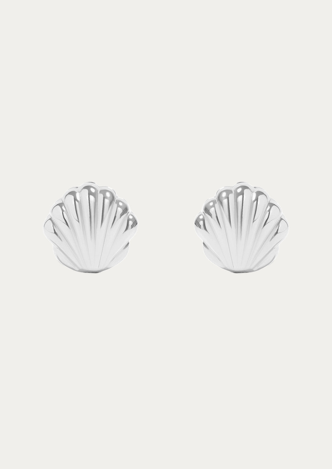 A pair of sterling silver huggie earrings in the shape of a concha shell 