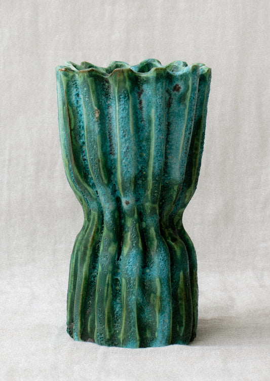 A ridge textured, turquoise hue ceramic vase.