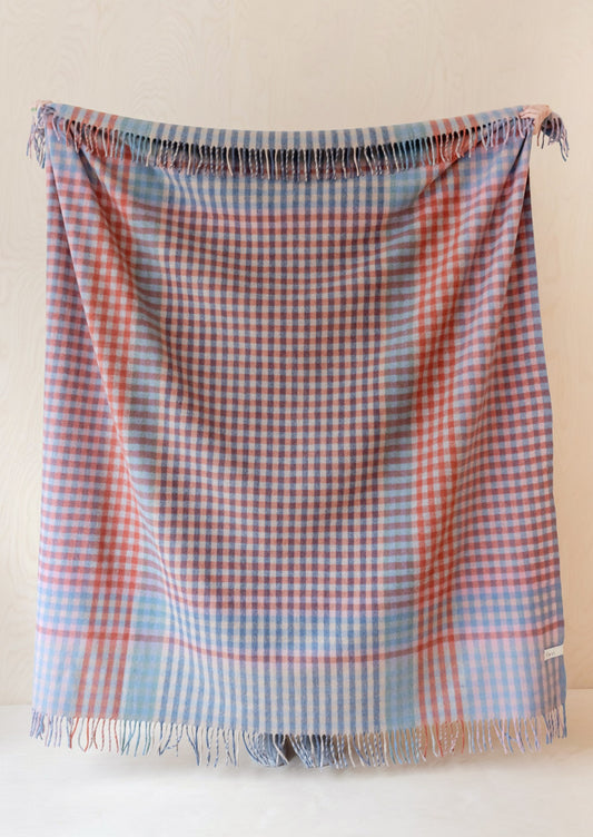 A gingham check patterned wool blanket in shades of red and cornflower blue.
