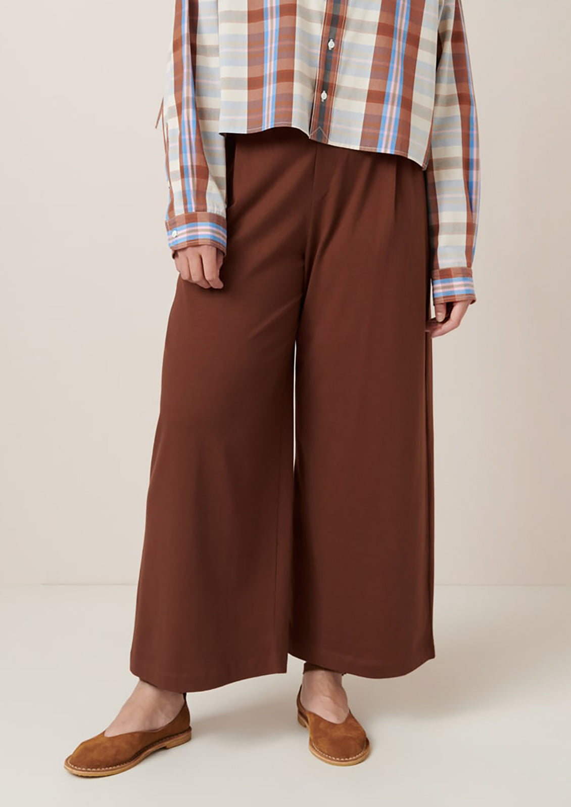 A person wearing a pair of wide leg pants in sequoia brown color.