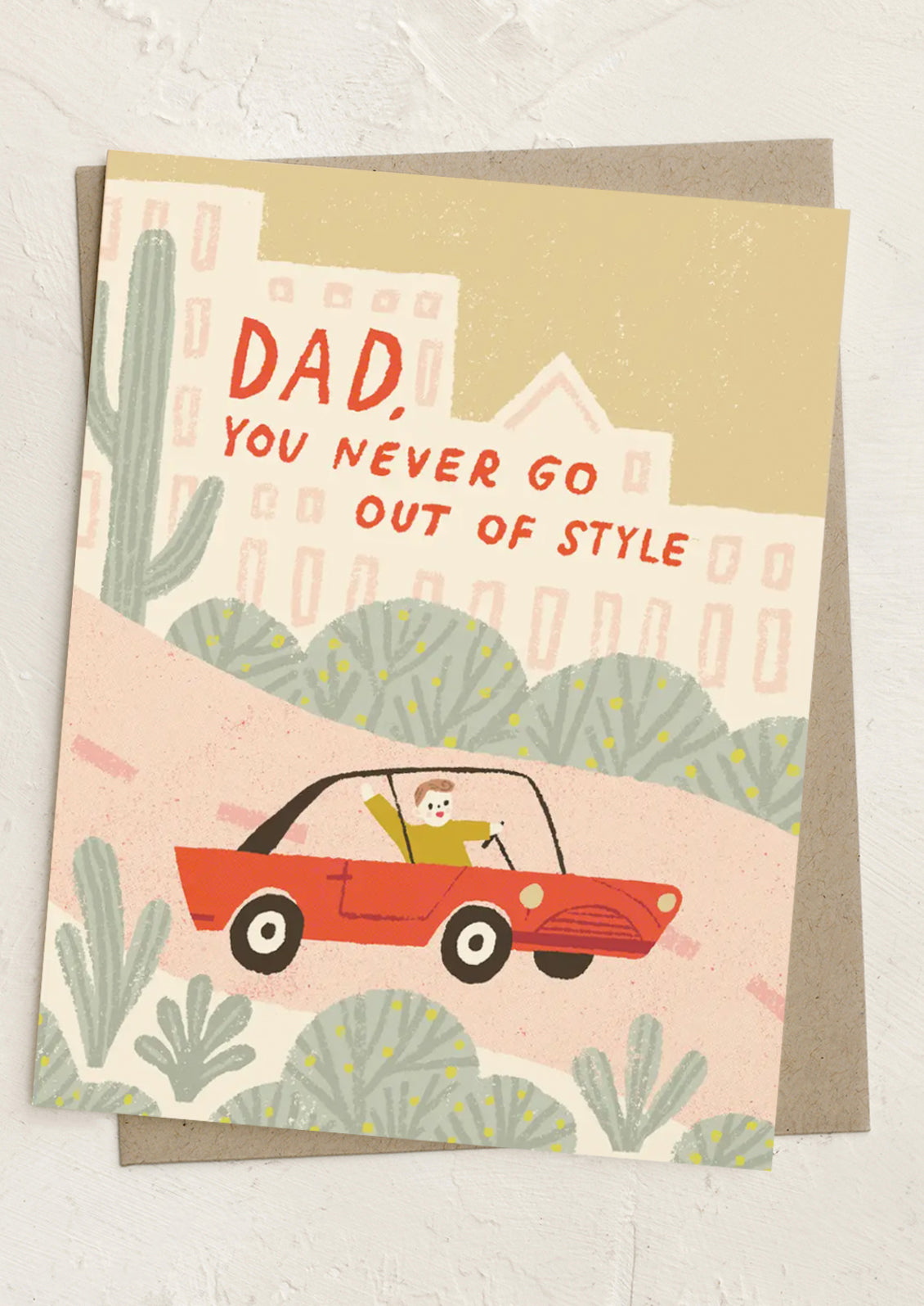 Greeting card with illustration of a man in a red car and text 'Dad, you never go out of style' on a beige background.