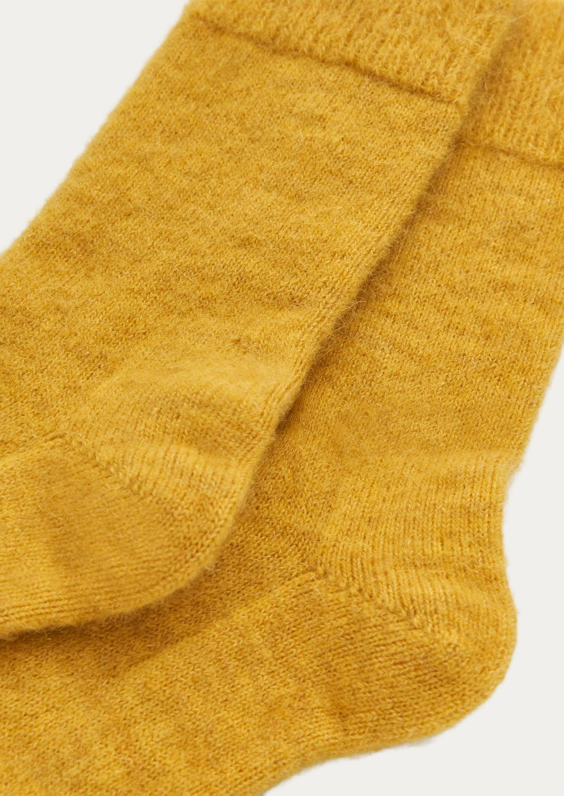 Closeup of a pair of textured alpaca blend, calf-length socks in bright yellow.