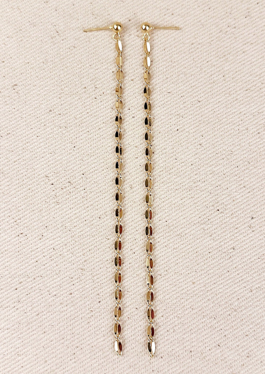 A pair of gold earrings with round ball post and long, dangling gold chain.