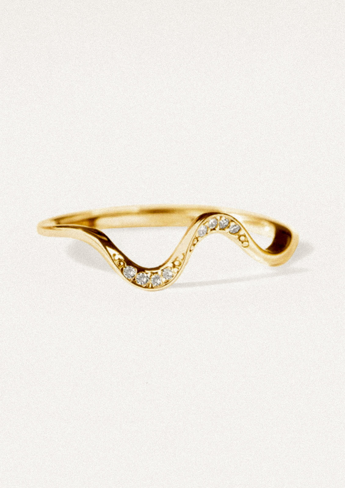 A wavy gold ring with crystal detailing.