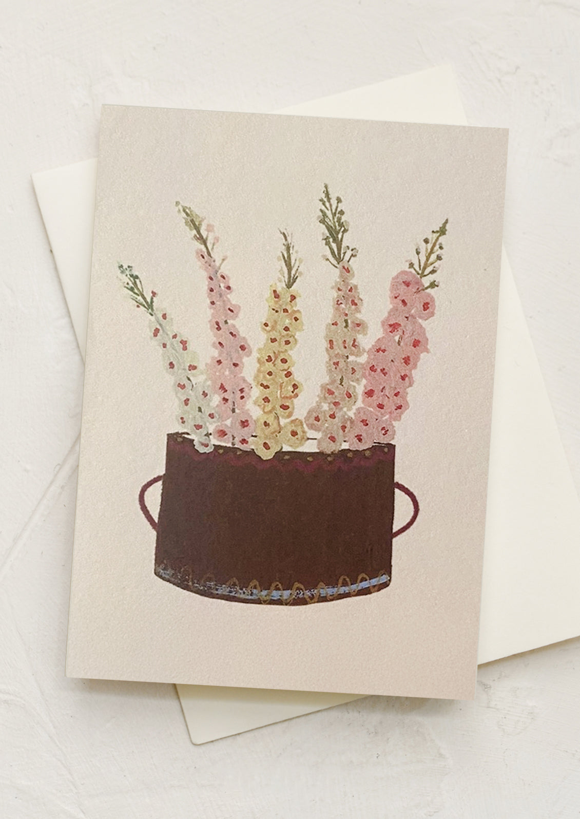 A mini greeting card in cream with illustration of delphiniums in basket.