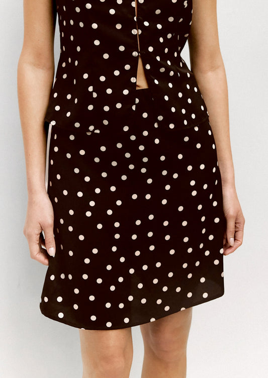 A person wearing a short skirt in brown with scattered cream polka dots.