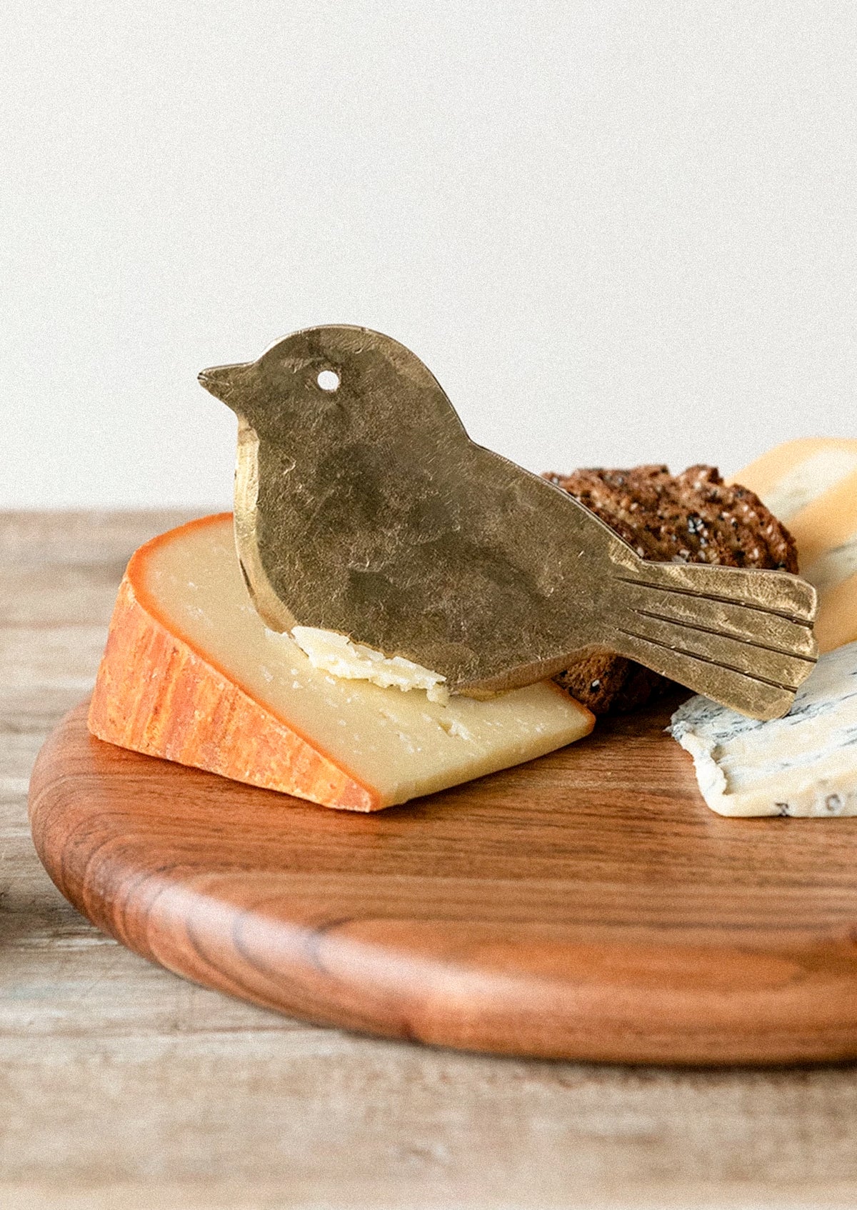 A brass cheese knife shaped like a bird.