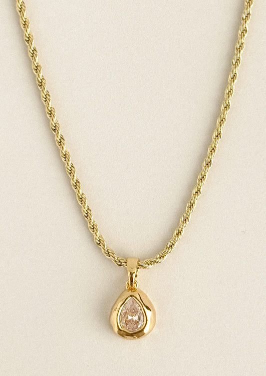 A gold necklace with a teardrop crystal charm.