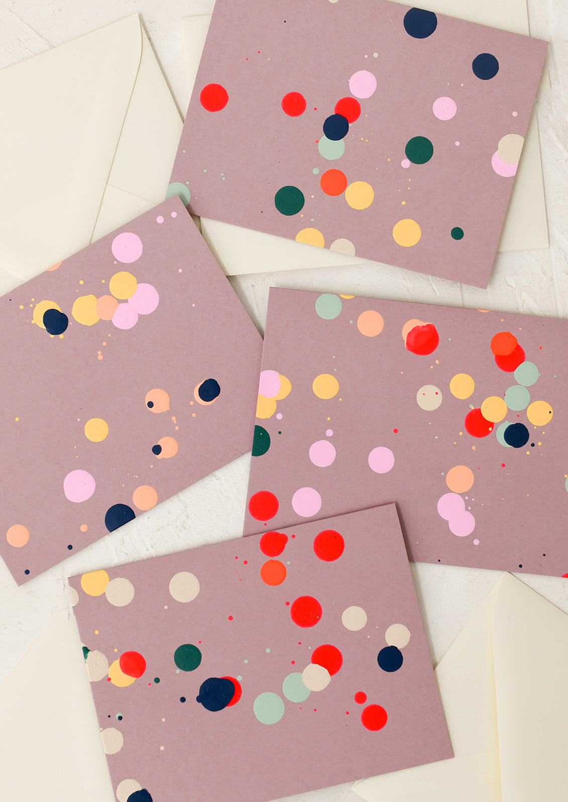 Four pink cards with colorful polka dots on a white surface