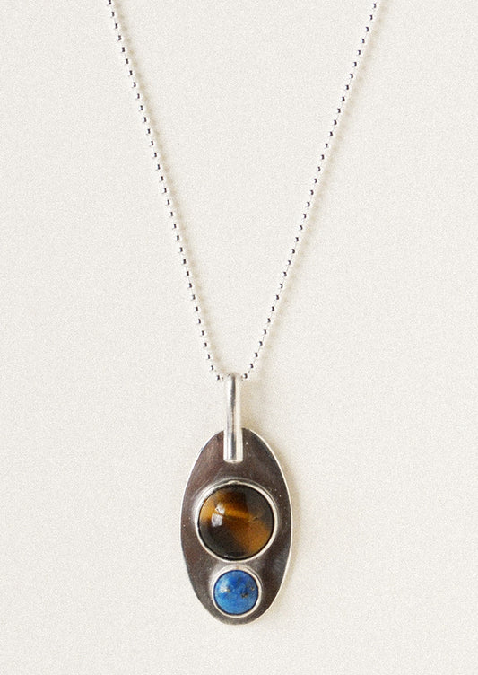 A silver necklace with pendant adorned with a brown gemstone and blue gemstone.