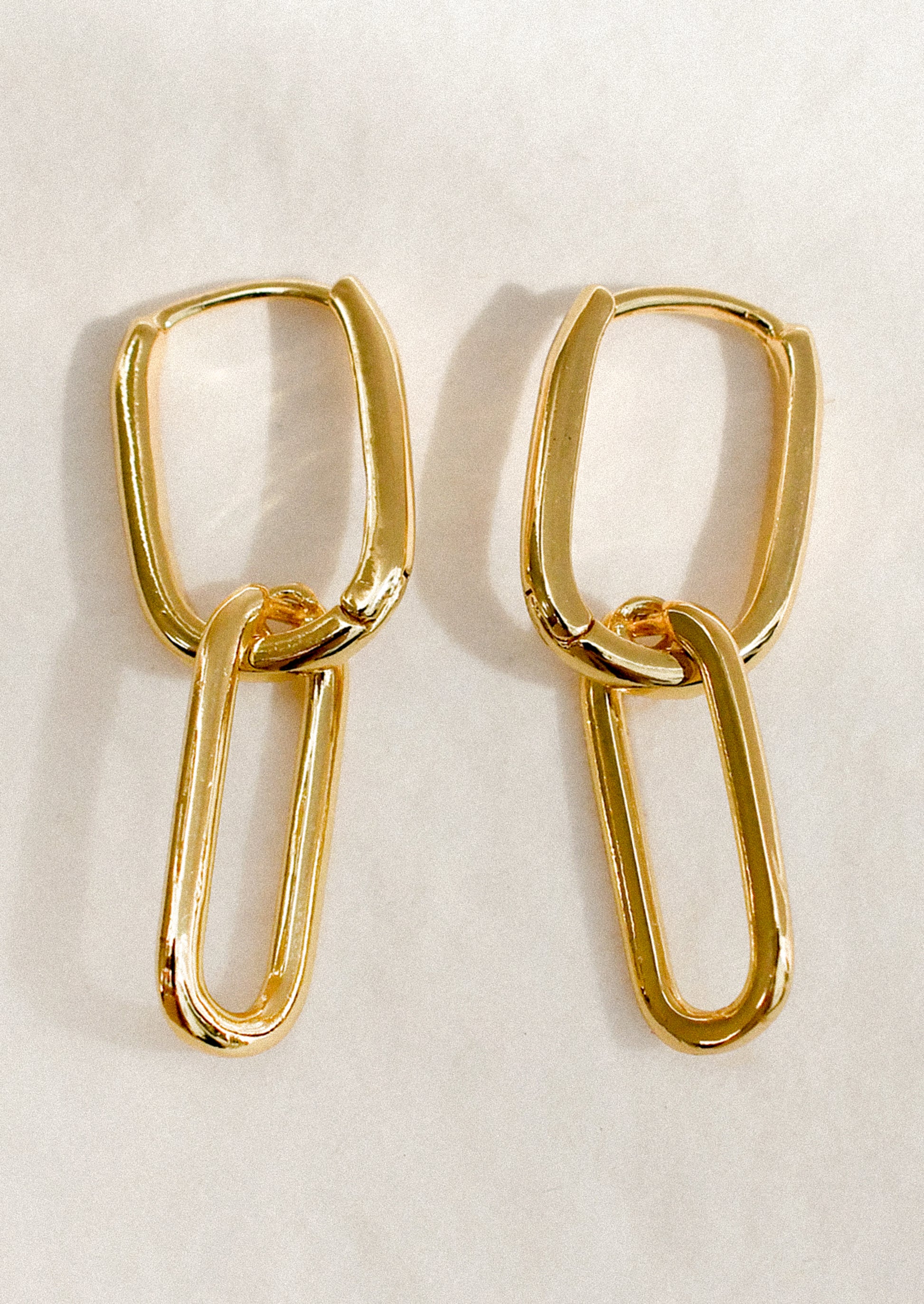 A pair of gold earrings with two oval links connected.